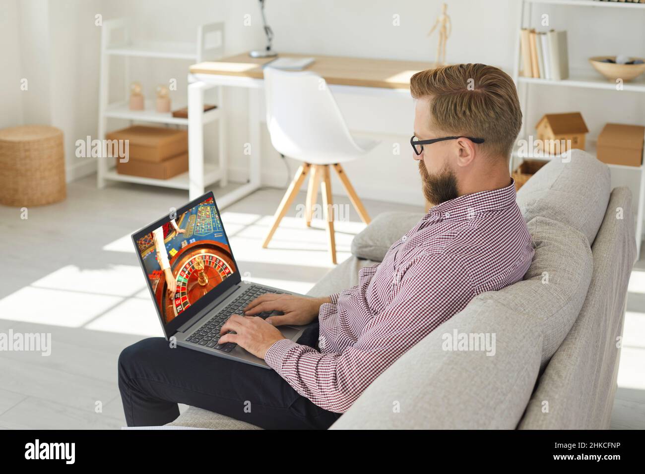 Man relax on sofa playing online casino game Stock Photo