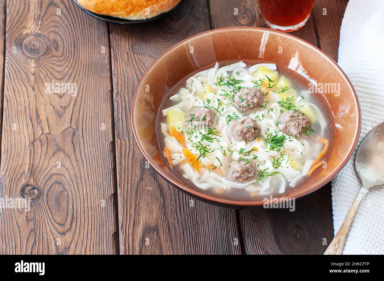 Homemade meatballs soup with noodles in a bowl on a wooden background. Stock Photo
