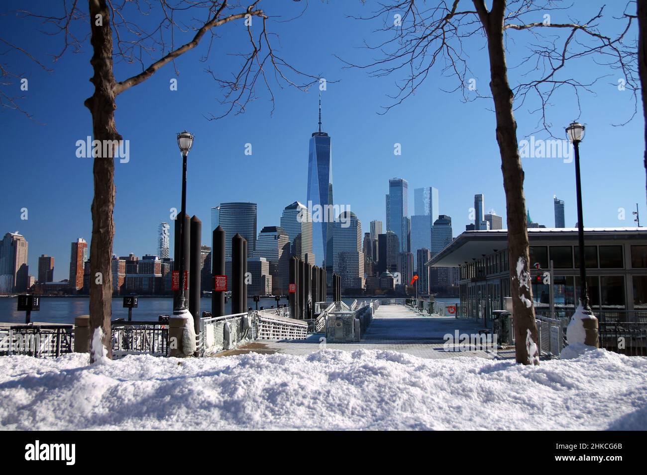 Downtown Manhattan and the Freedom tower with a ferry dock and the snow from the other side of the Hudson River in Jersey City Stock Photo