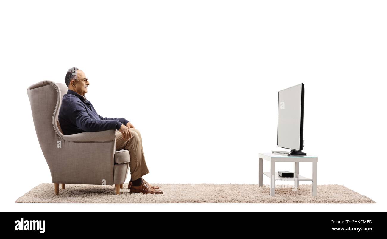 Profile shot of a casual mature man sitting in an armchair and watching