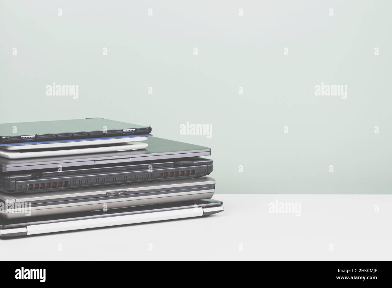 Pile of old used laptop computers for recycling on white table. Planned