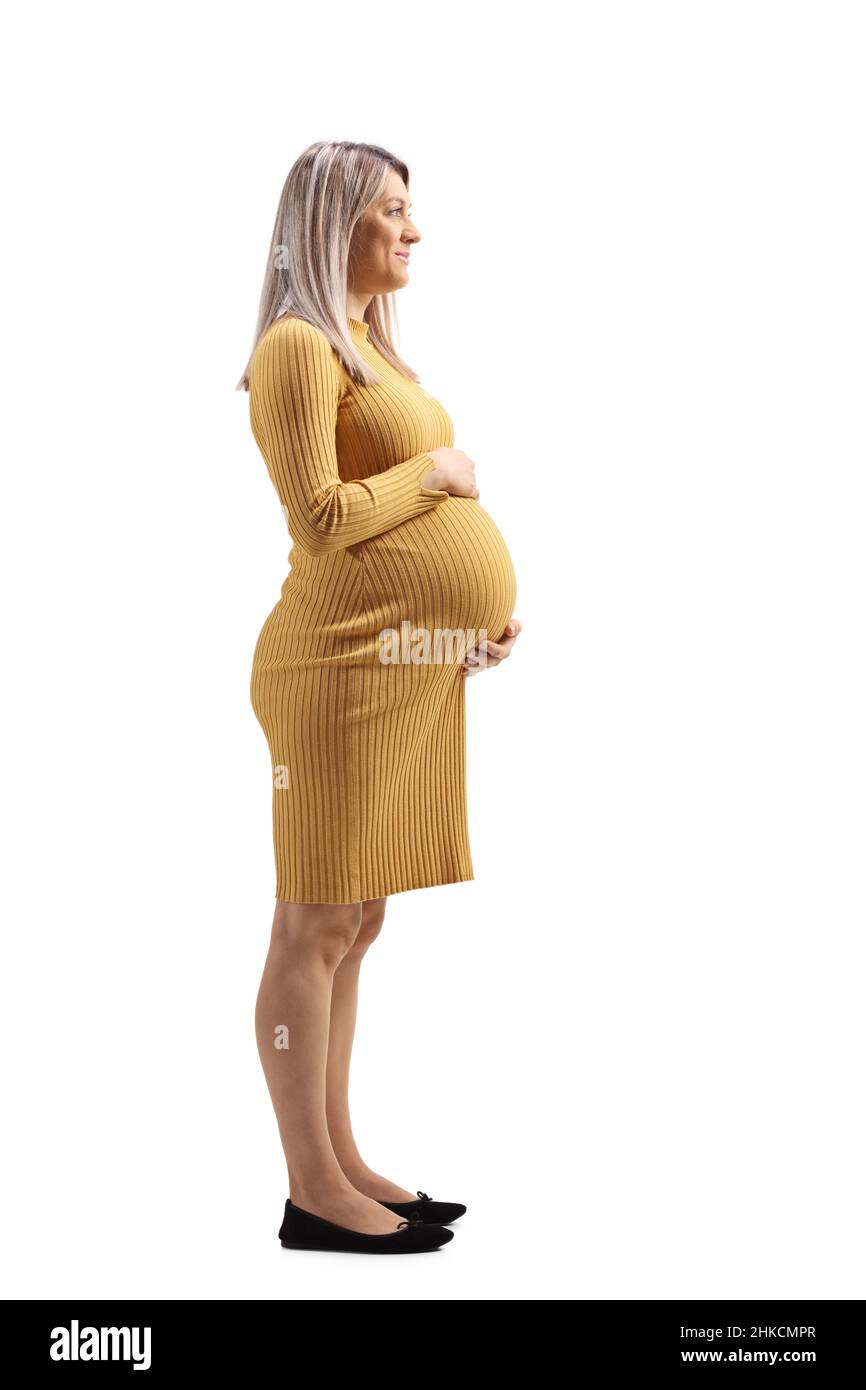 Full length profile shot of a pregnant woman in a yellow dress holding her tummy isolated on white background Stock Photo