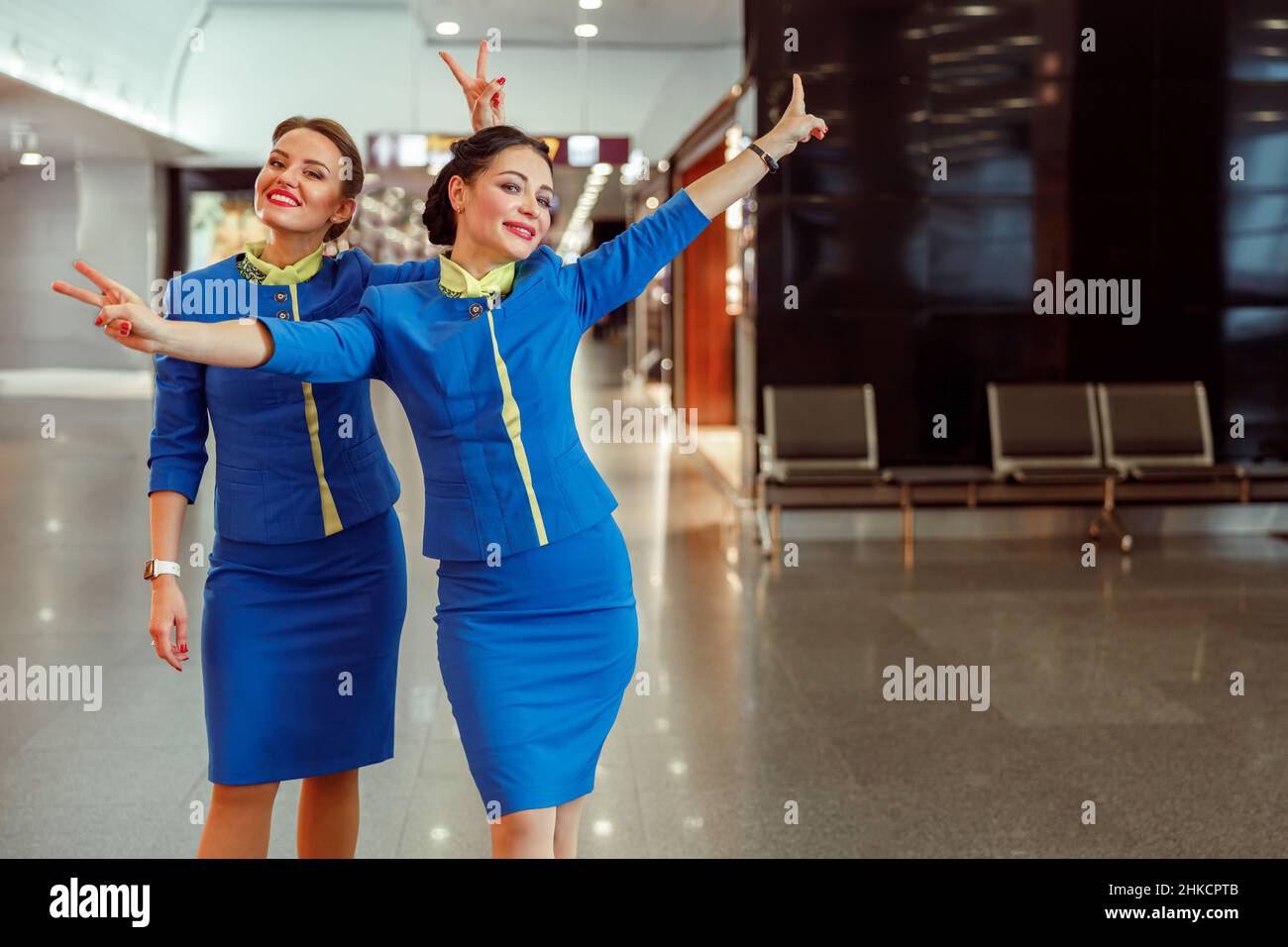 Cheerful women stewardesses showing victory gesture at airport Stock