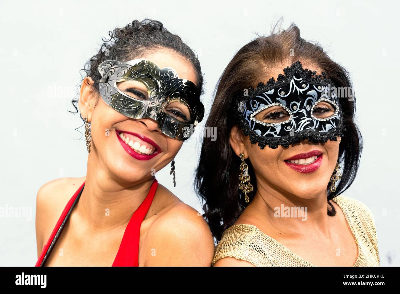 Close-up of face of two women wearing Venice Carnival mask against light background. Salvador, Bahia, Brazil. Stock Photo