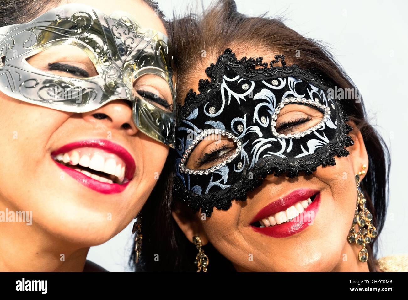 Close-up of face of two women wearing Venice Carnival mask against light background. Salvador, Bahia, Brazil. Stock Photo