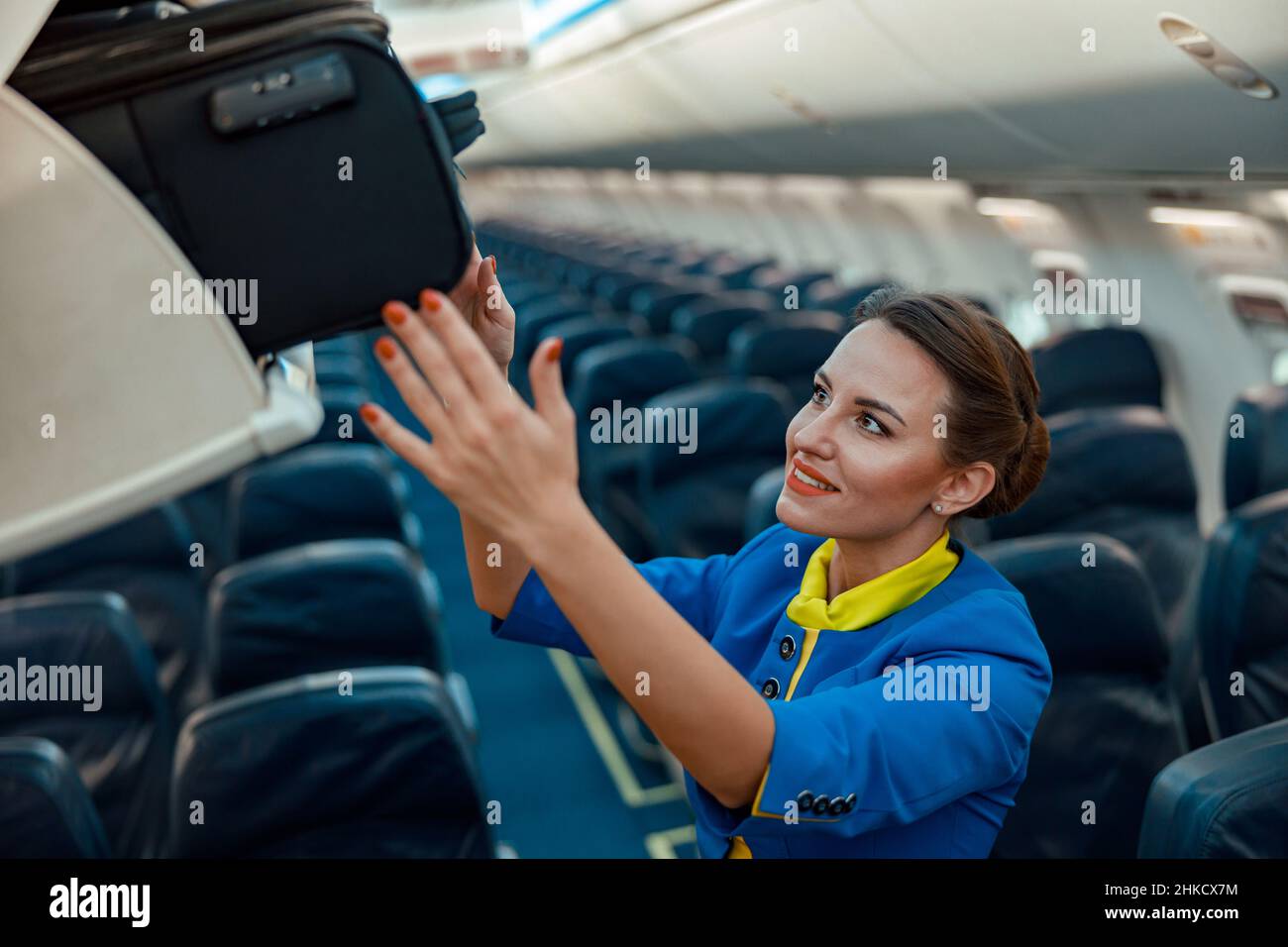 Air hostess putting travel bag in overhead luggage bin in airplane