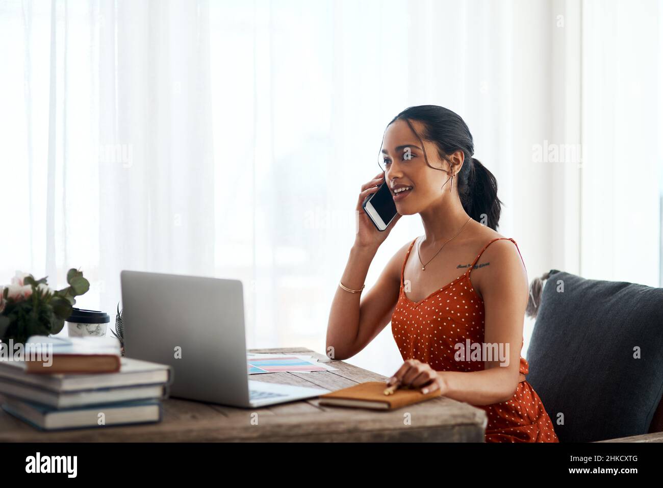 How may I help you. Cropped shot of an attractive young businesswoman sitting in her office and using her laptop while on a phone call. Stock Photo