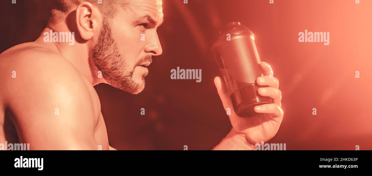Young man drinks water in the gym. Man at gym and holding bottle of ...