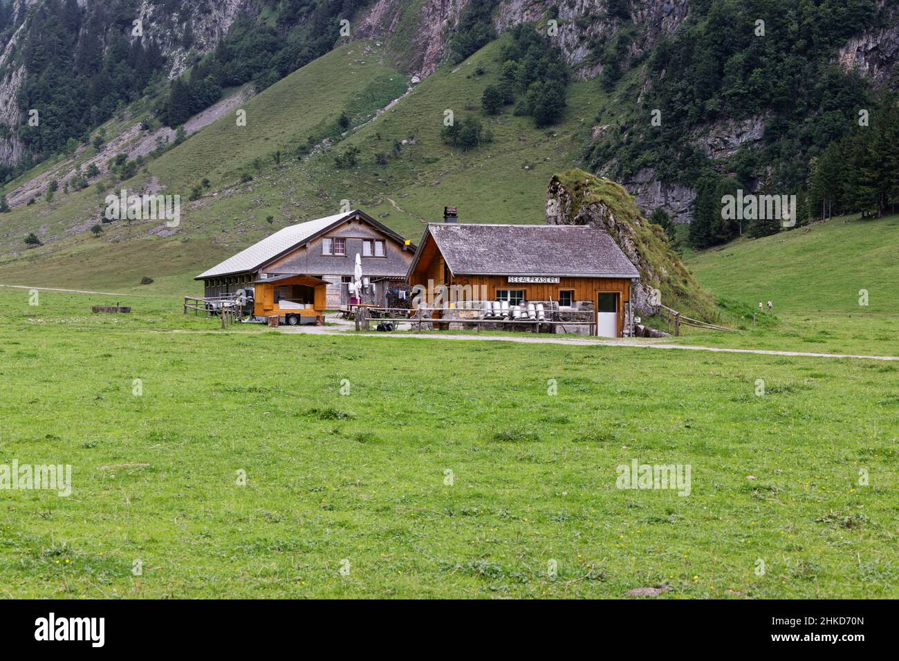 19.08.2021 Seealpsse Switzerland: old style alpine dairy built next to a rock wall, empty milk cans in front of the house, german alpine dairy sign wi Stock Photo