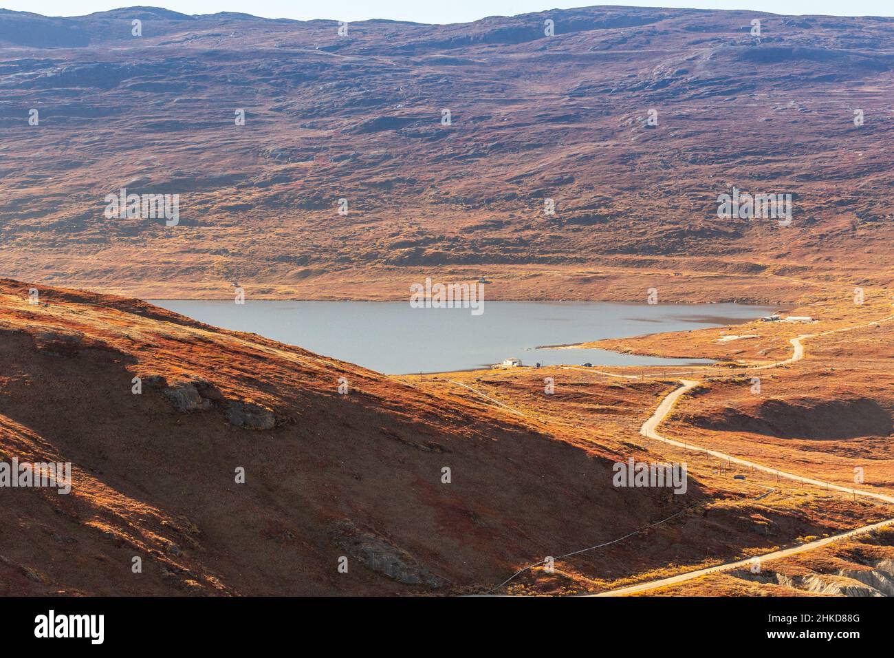 Autumn greenlandic orange tundra landscape with road to the lake and mountains in the background, Kangerlussuaq, Greenland Stock Photo