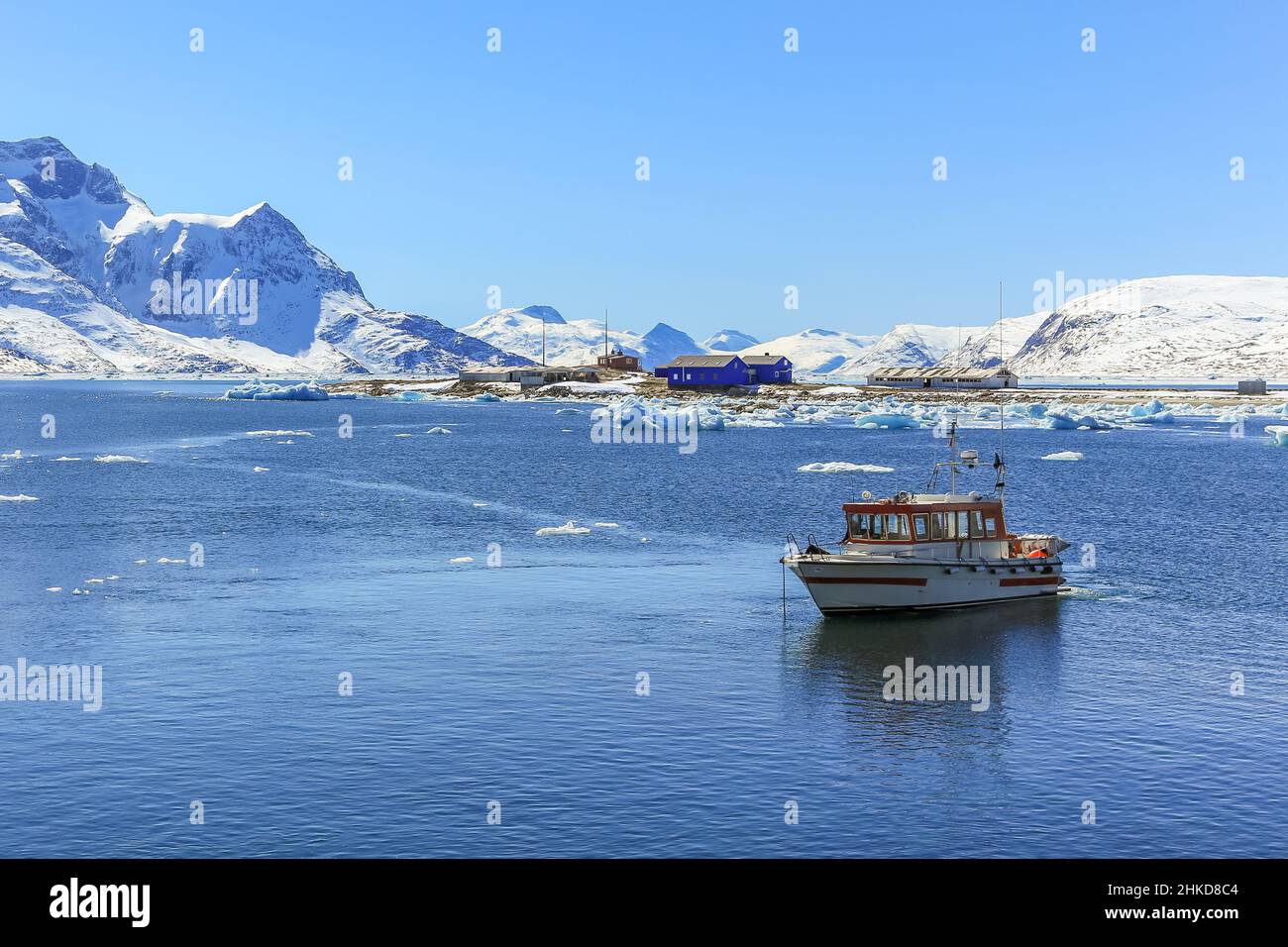 Boat anchored in the lagoon and Qoornoq former fishermen village in the middle of Nuuk fjord, Greenland Stock Photo