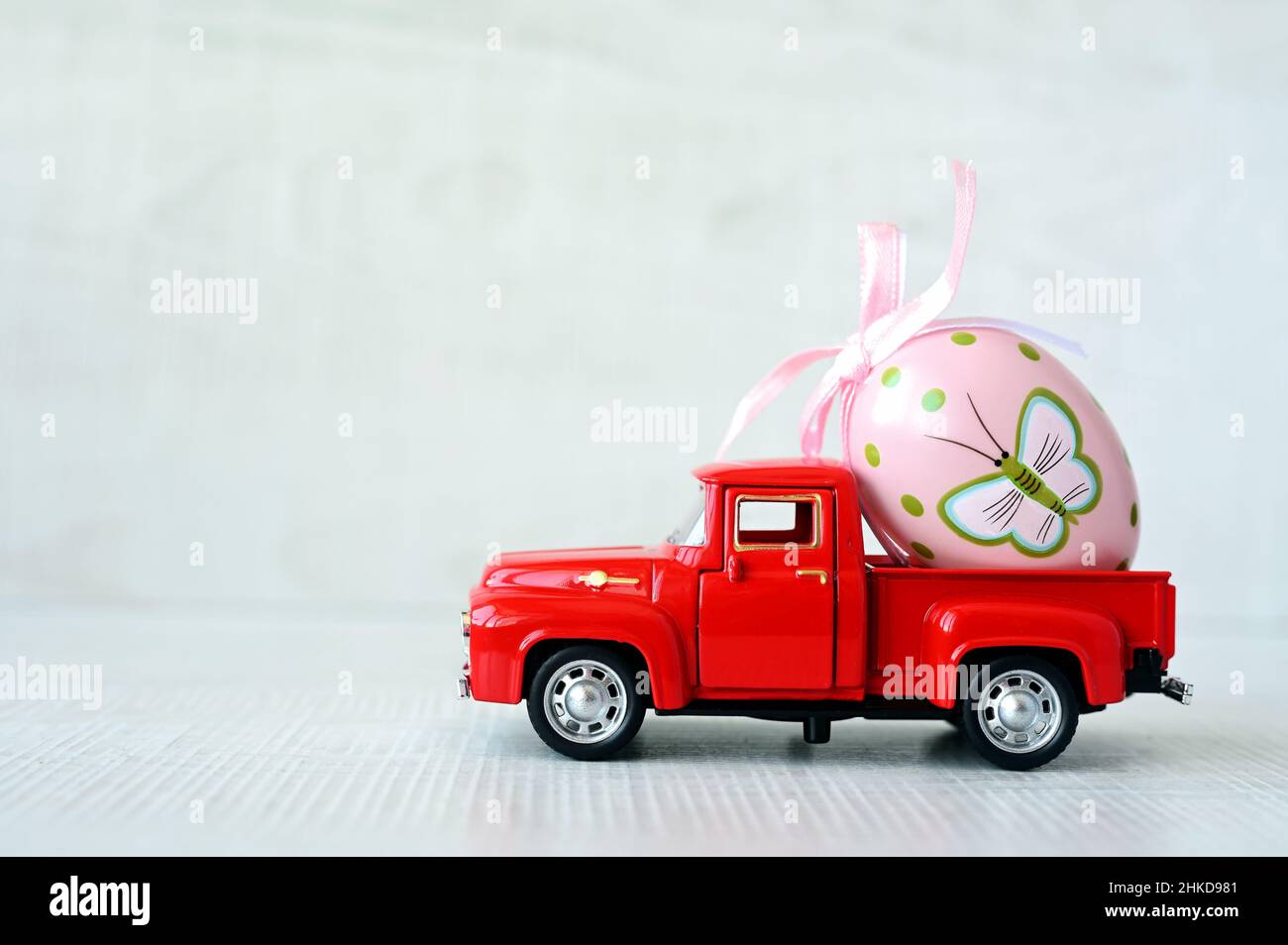 One Easter egg on a small car on a grey background. Copy space. Easter card. Stock Photo