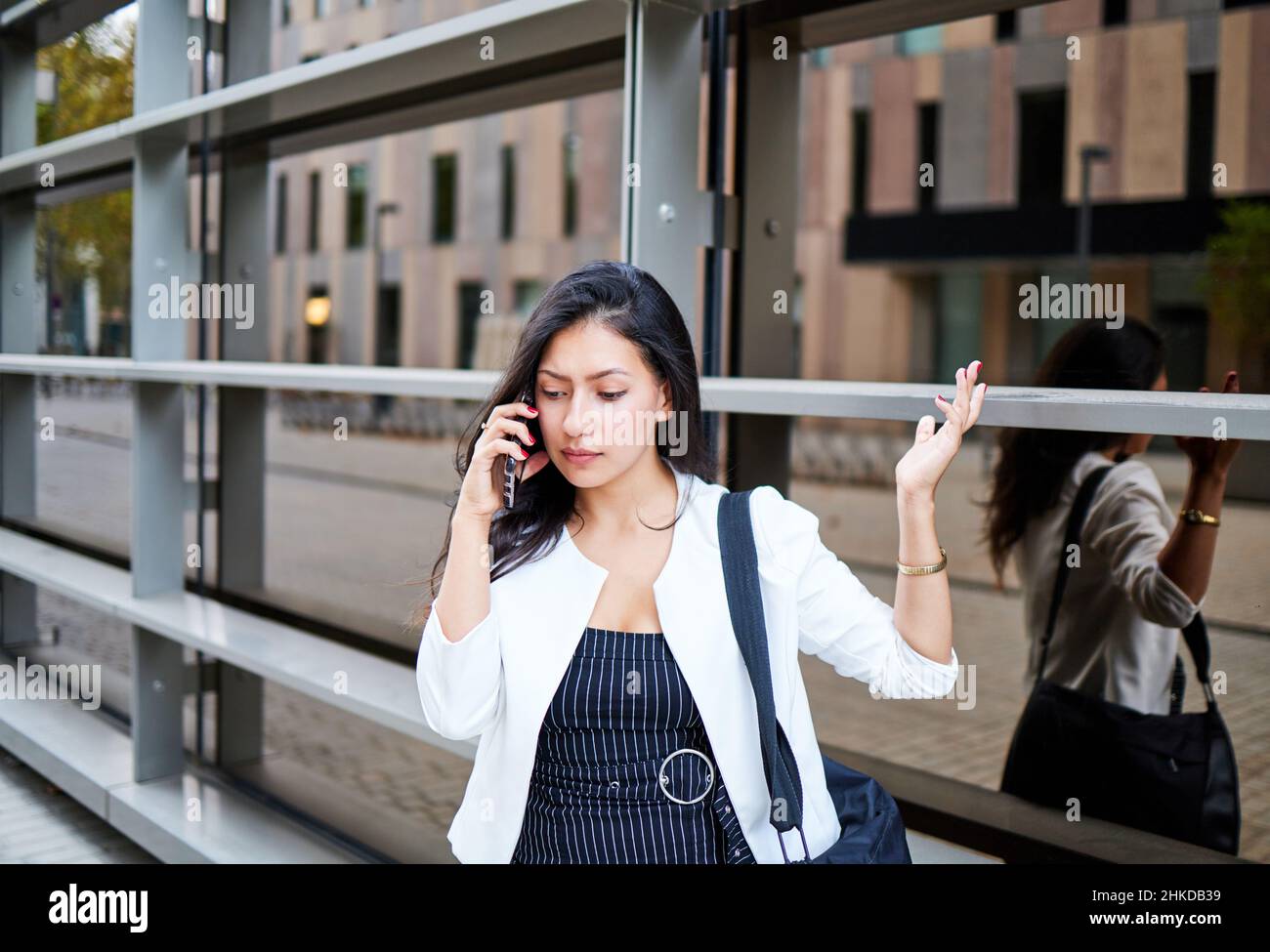 Young business girl with angry face talking on mobile phone. She is ...