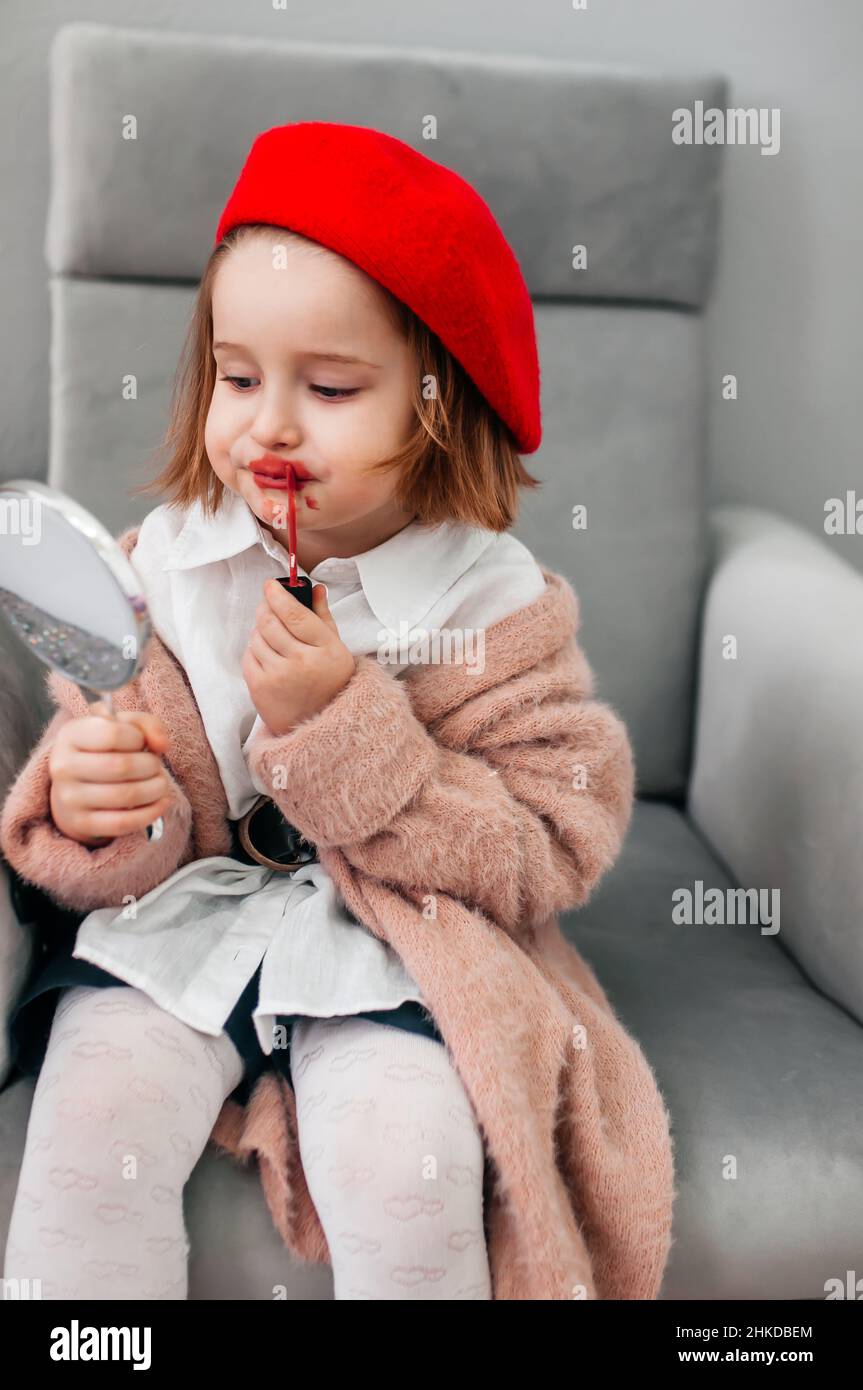 Red lipstick, bright baby lips. Fashionable child in a red beret and