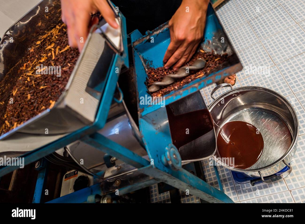 A fresh cacao liquor flows out of a grinder machine in artisanal chocolate manufacture in Xochistlahuaca, Guerrero, Mexico. Stock Photo