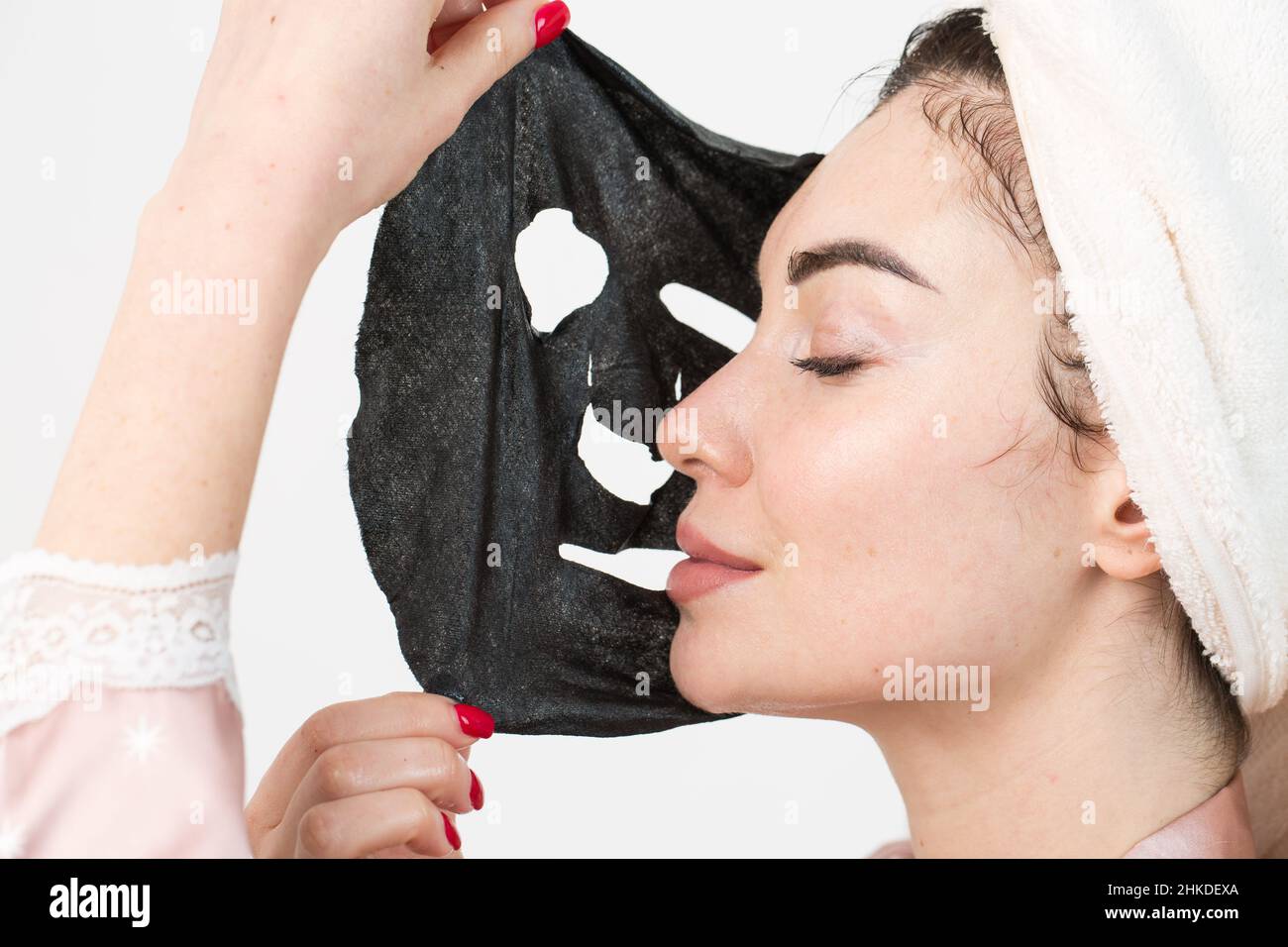 Face care and beauty treatments. Woman with a sheet moisturizing mask on her face isolated on white background. Stock Photo