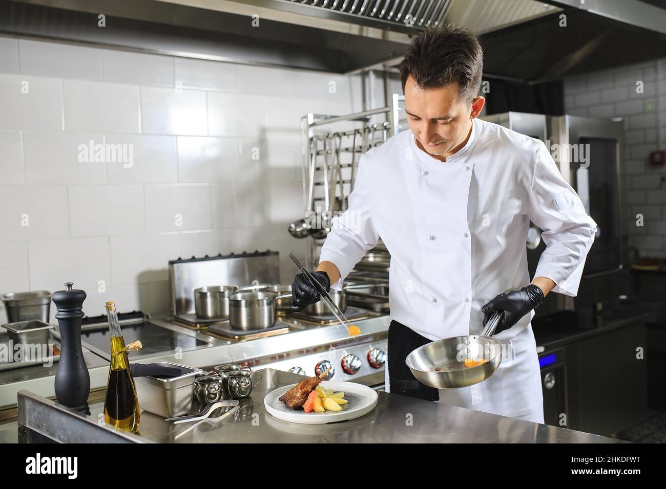 Chef Preparing Dish In Kitchen. Decorating Dish Stock Photo