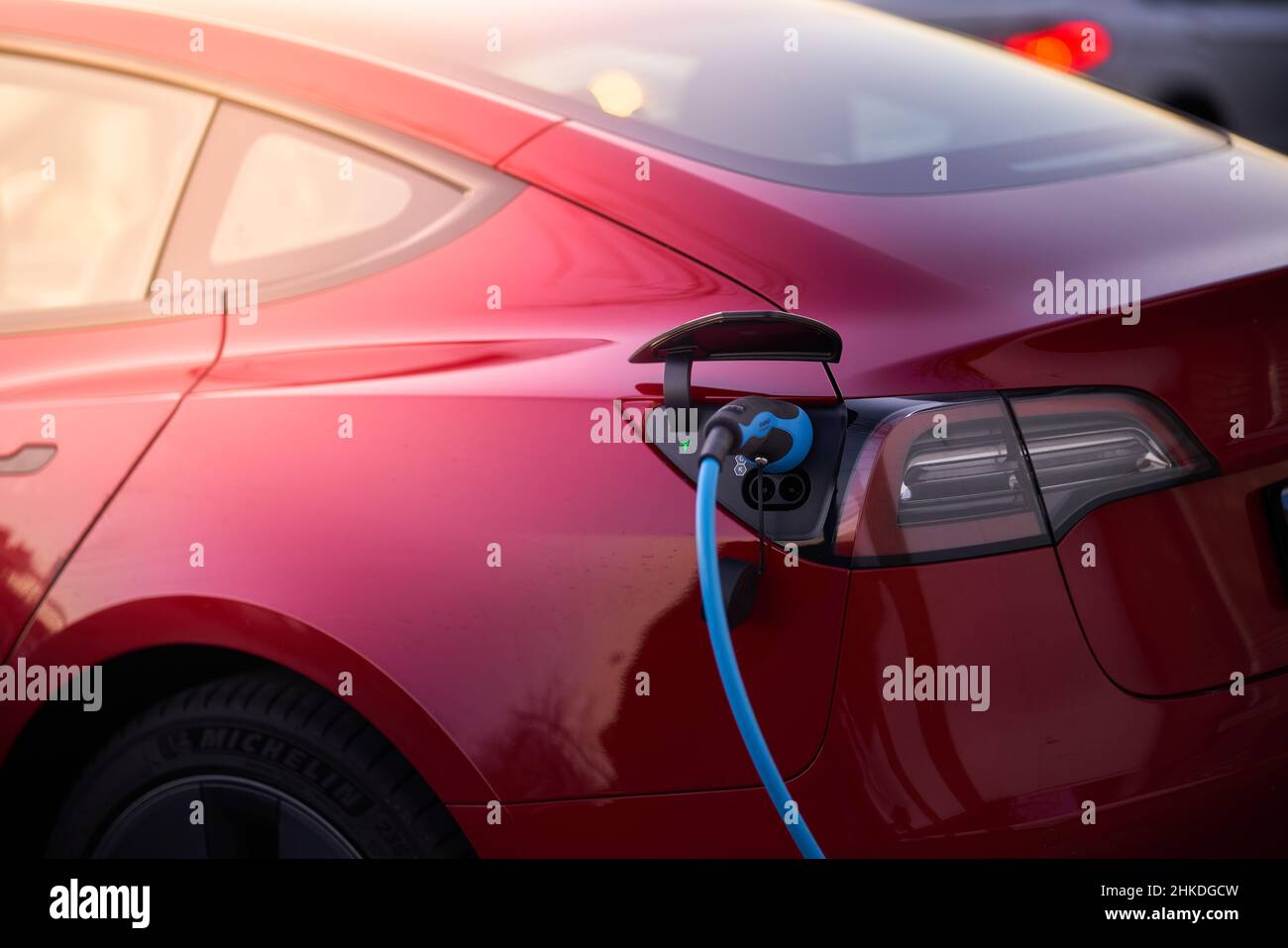 Modern red electric vehicle at the time of charging connected to