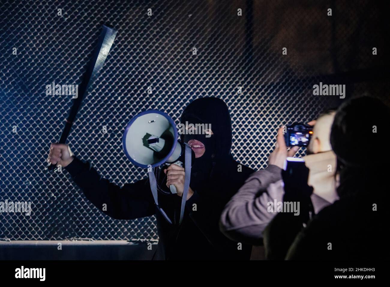 Masked rebel with bat and megaphone. Journalists are making pictires Stock Photo