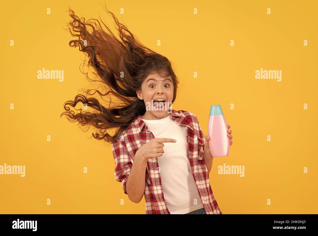 happy teen girl with long curly hair hold shampoo bottle, keratin Stock Photo