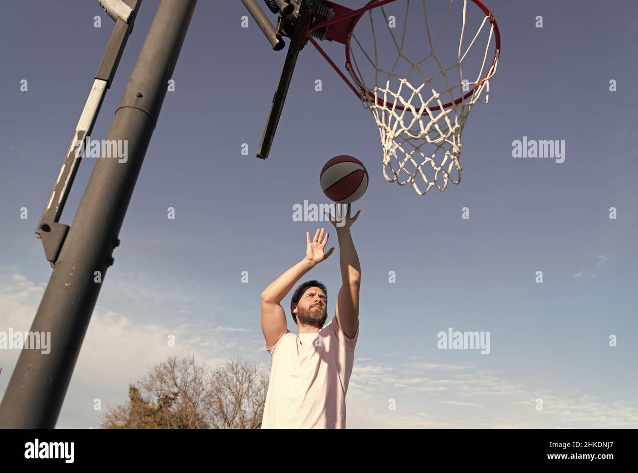 man throw ball in basket playing basketball in summer sport playground