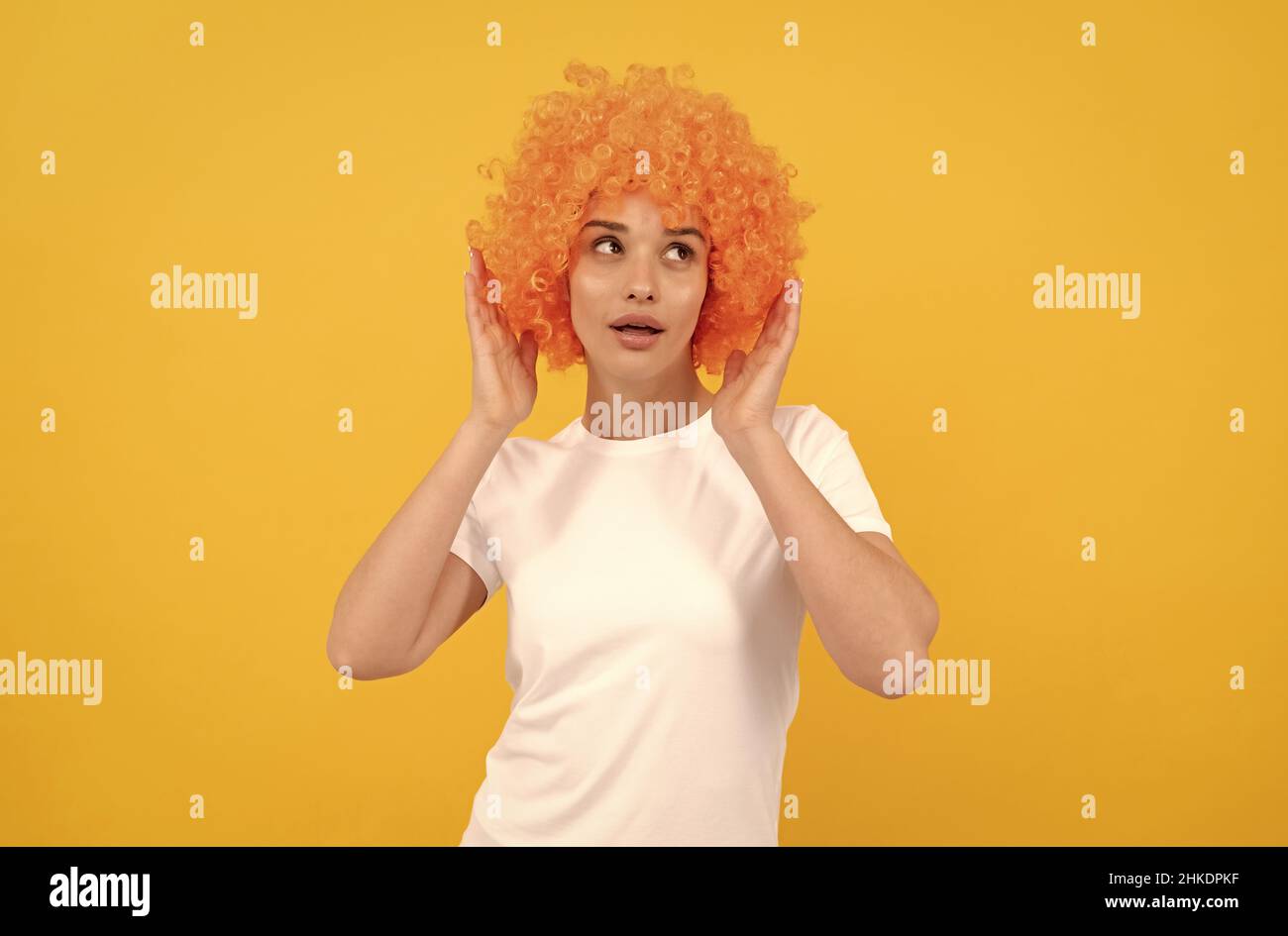 amazed fancy party look. freaky woman in clown wig on yellow background. express positive emotions. Stock Photo