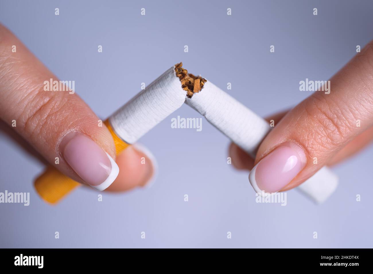 Closeup woman hands with broken cigarette. Stop smoking, quit smoking