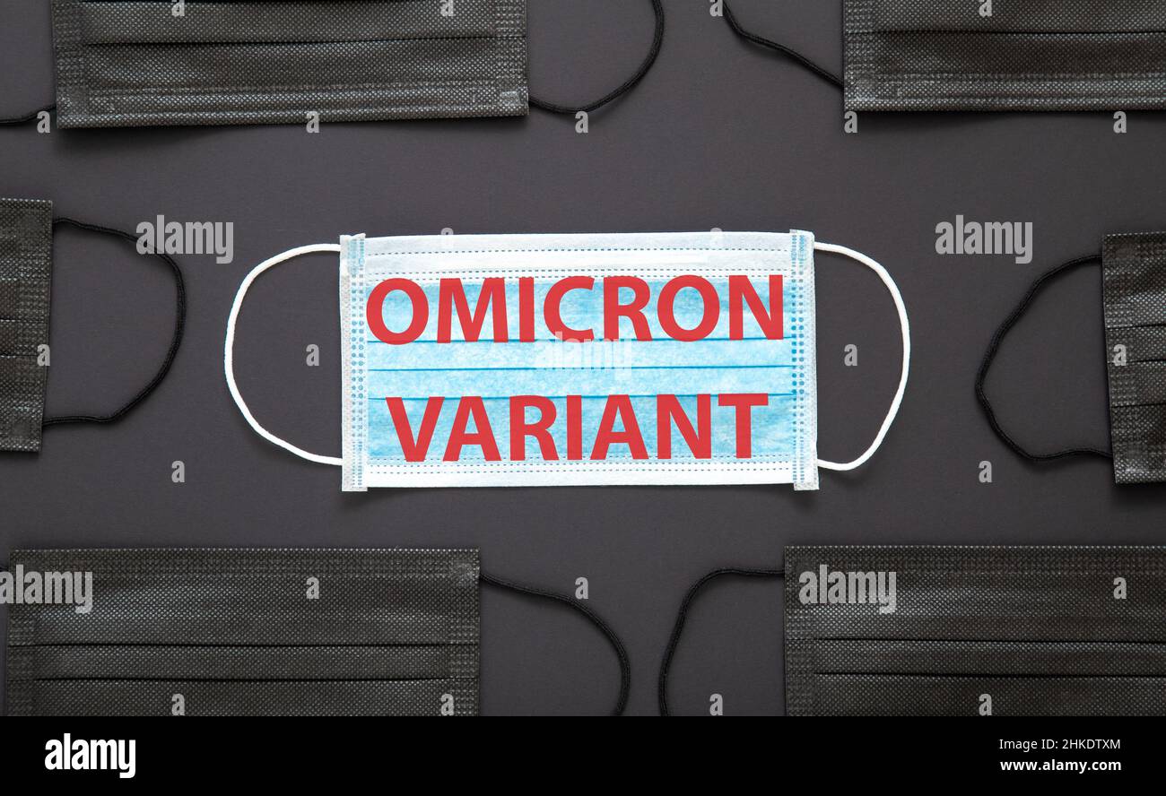 New Omicron variant covid 19 text on face mask isolated on black background. Omicron positive text warning sign on medical protective black mask. Stock Photo