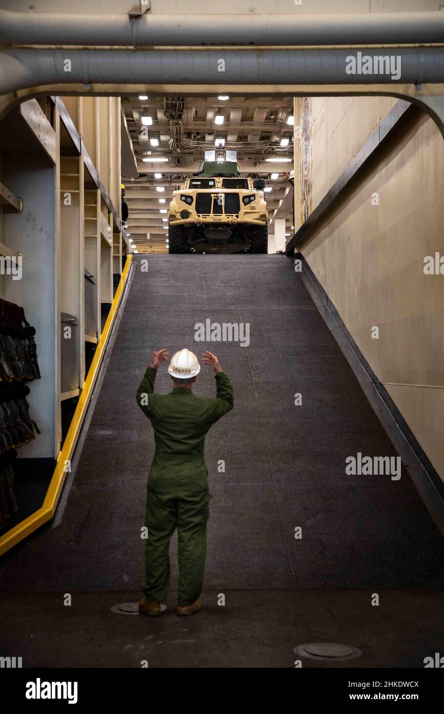 220201-N-PC065-1133 ATLANTIC OCEAN – Lance Cpl. Jose Liranzo, attached to the 22nd Marine Expeditionary Unit, directs a Joint Light Tactical Vehicle down a ramp aboard the San Antonio-class amphibious transport dock ship USS Arlington (LPD 24), Feb. 1, 2022. The Kearsarge Amphibious Ready Group (ARG) and 22nd Marine Expeditionary Unit (MEU) are underway conducting a Composite Training Unit Exercise (COMPTUEX). COMPTUEX is the final pre-deployment exercise that certifies the Kearsarge ARG and 22nd MEU's ability to conduct military operations through joint planning, and execute challenging and r Stock Photo