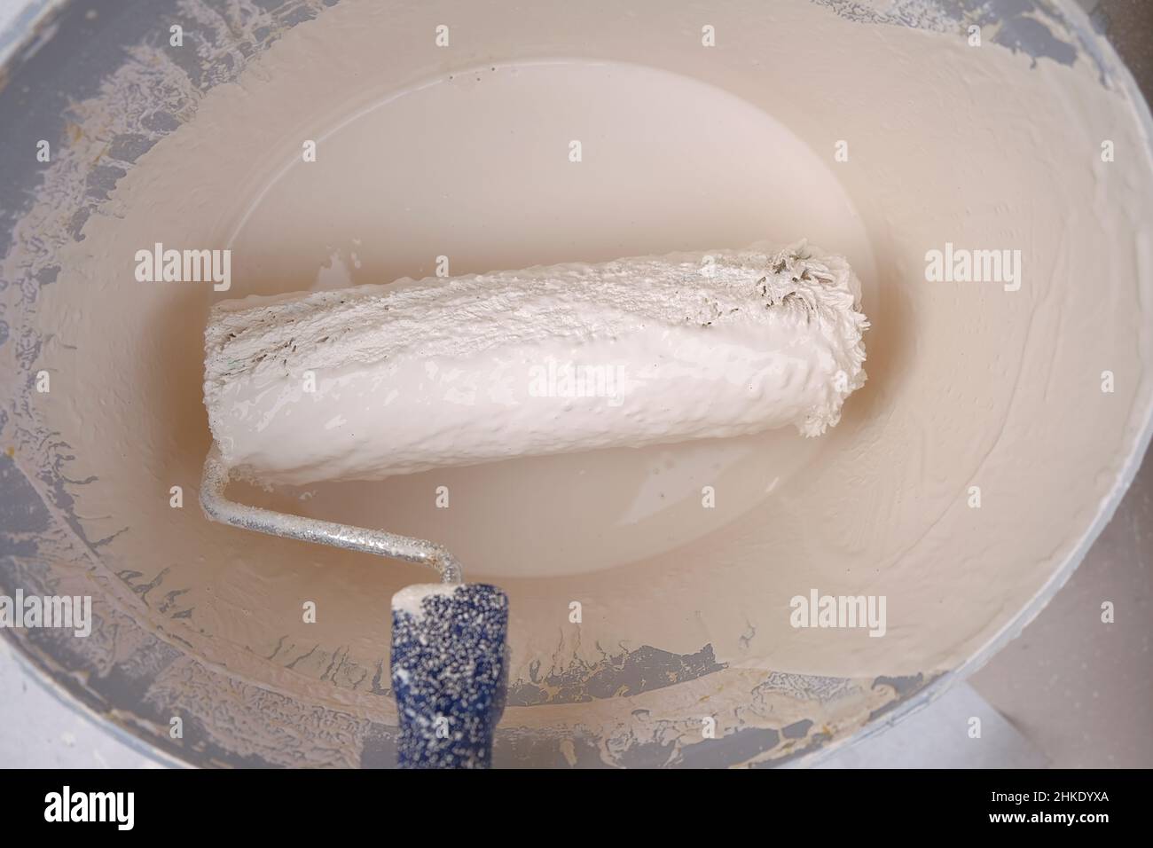 Roller and paint. Construction roller in a bucket with beige paint