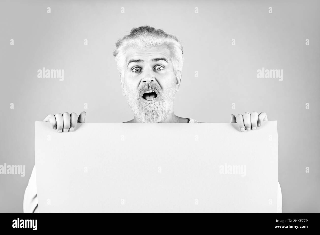 Business man showing thumb up holds sign board. Colorful studio portrait on isolated background. Happy man holding empty white board. Stock Photo