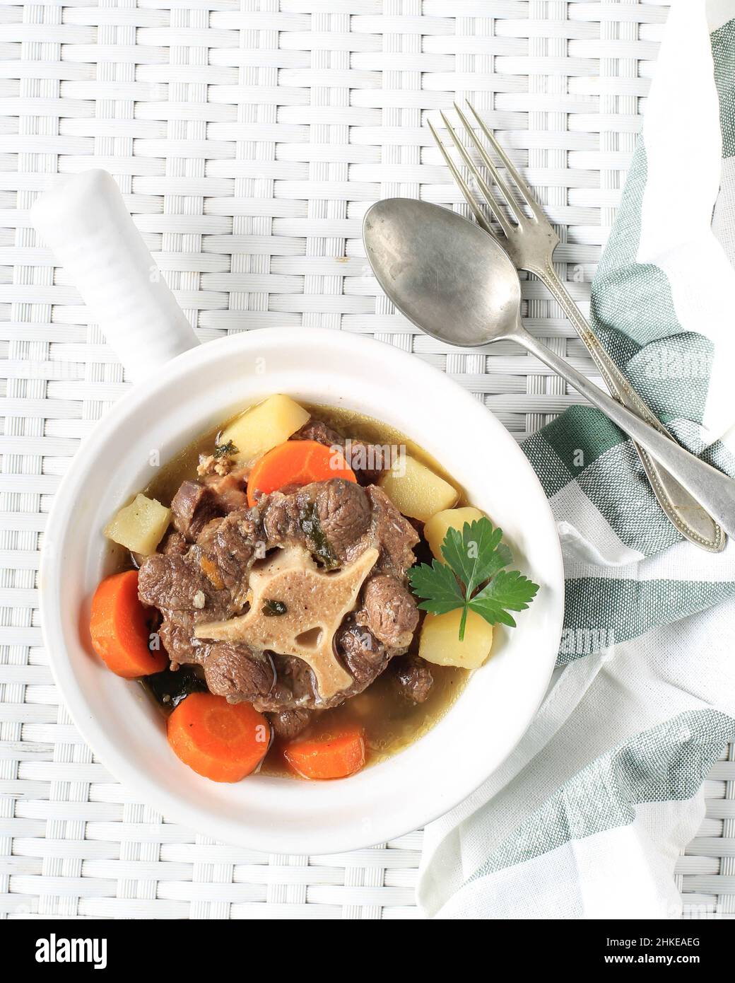 Sop Buntut or Oxtail Soup Served in White Bowl on White Woven Table. Top View Stock Photo