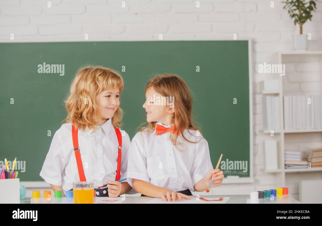 Cute school friends kids drawing and painting at school. Friendly boy an girl funny pupils draw. Friendship in school. Siblings drawing with pencil Stock Photo