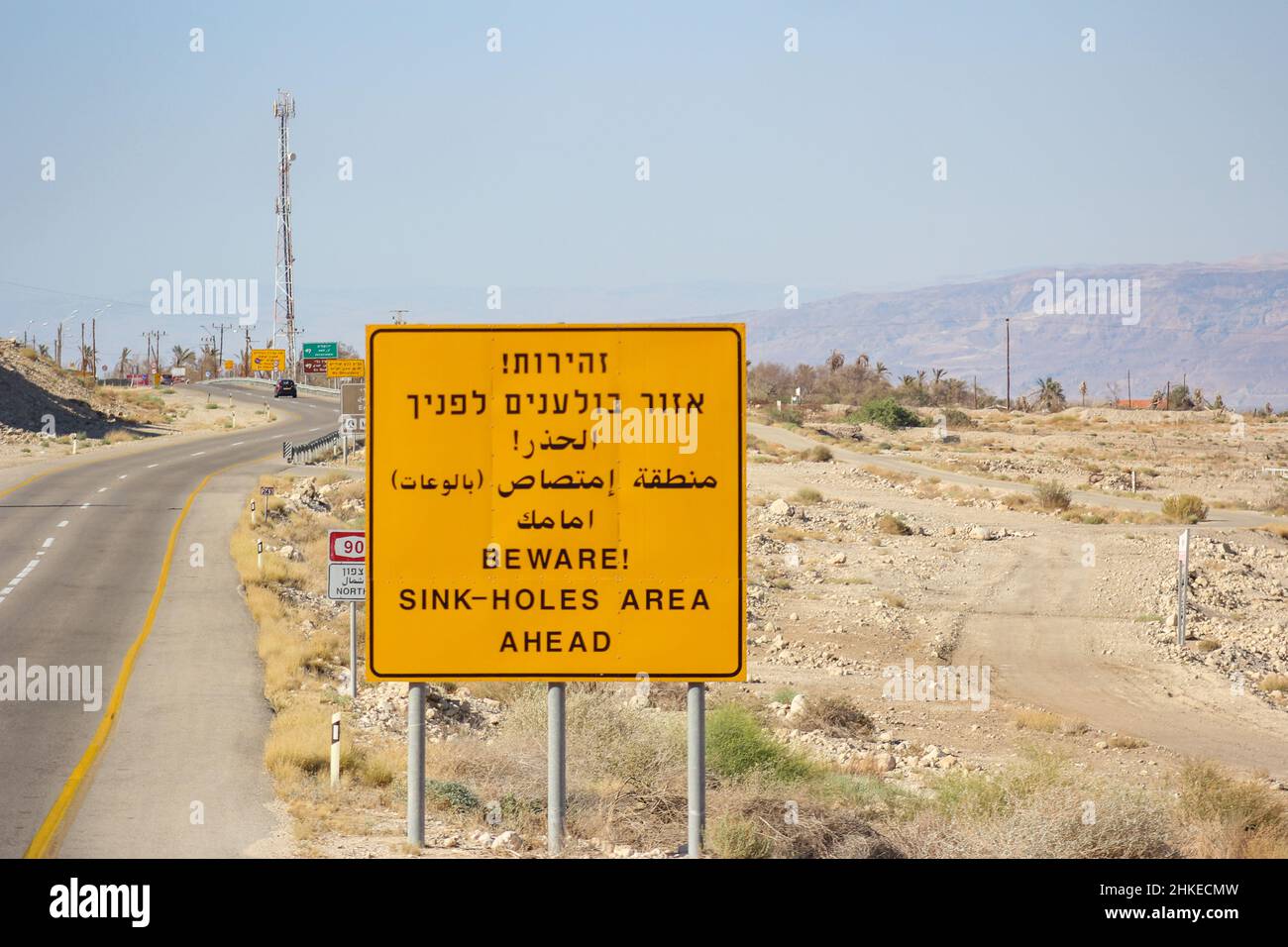 A cautionary trilingual sign along Israeli Highway 90 warns of sink-holes in this area of the Judean Desert near the Dead Sea in the West Bank. Stock Photo