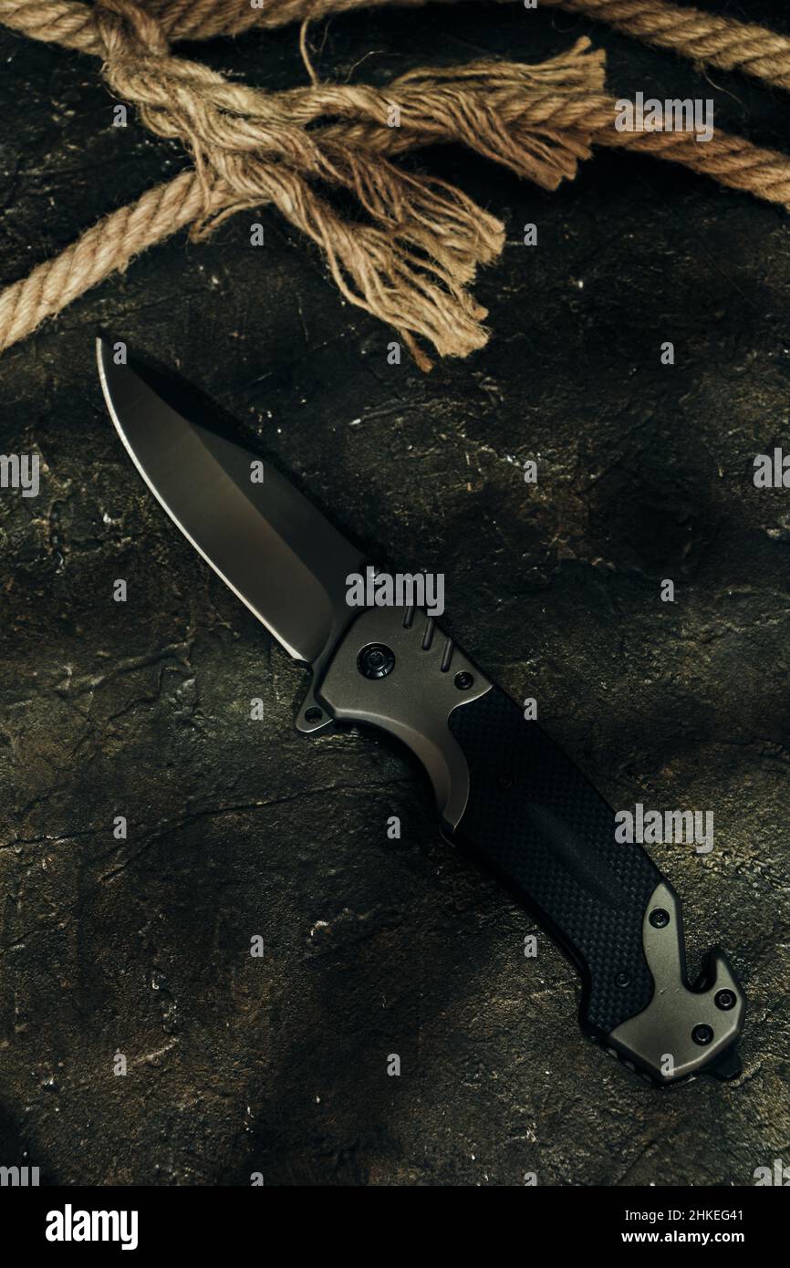 Tactical knife and cut rope on rocky background.Survival and adventure