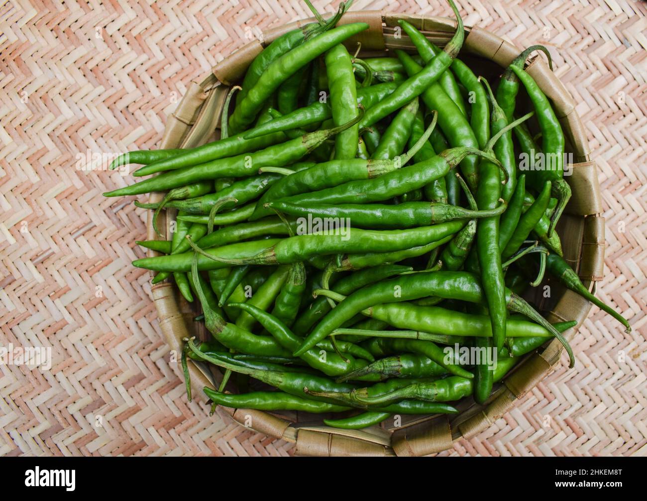 Thin and long light green coloured Green chillies heap in wicker basket