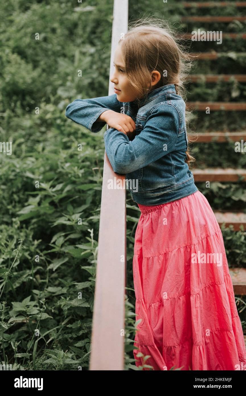 prepuberal girl thoughtful candid eight year old kid girl stands on staircase with grass  and enjoying nature. prepubertal age of children and their lives, mind  psycho Stock Photo - Alamy