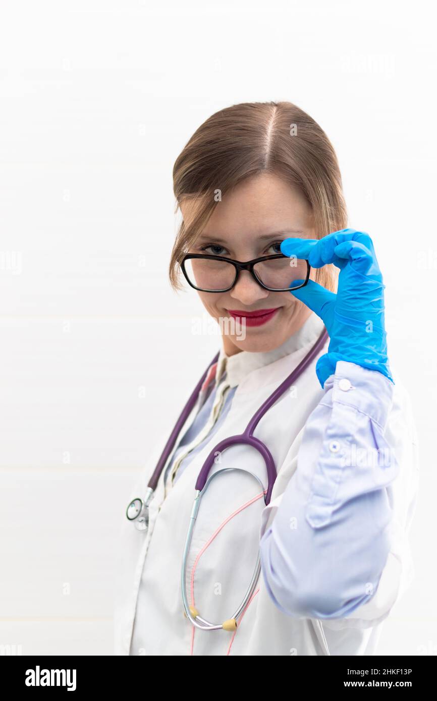 Beautiful young doctor woman in medical gloves and glasses with a stethoscope in a hospital on a white background. Selective focus. Portrait. Close-up Stock Photo