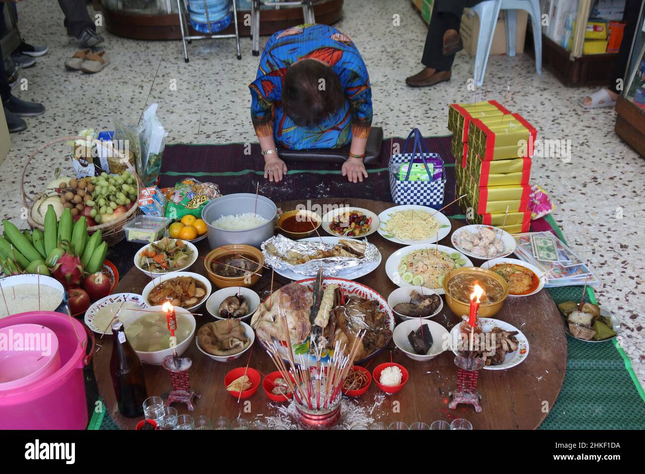 A woman prays in here home and make offerings of food to the spirits for luck and prosperity in Chinese new year, Chinatown, Bangkok,Thailand Stock Photo