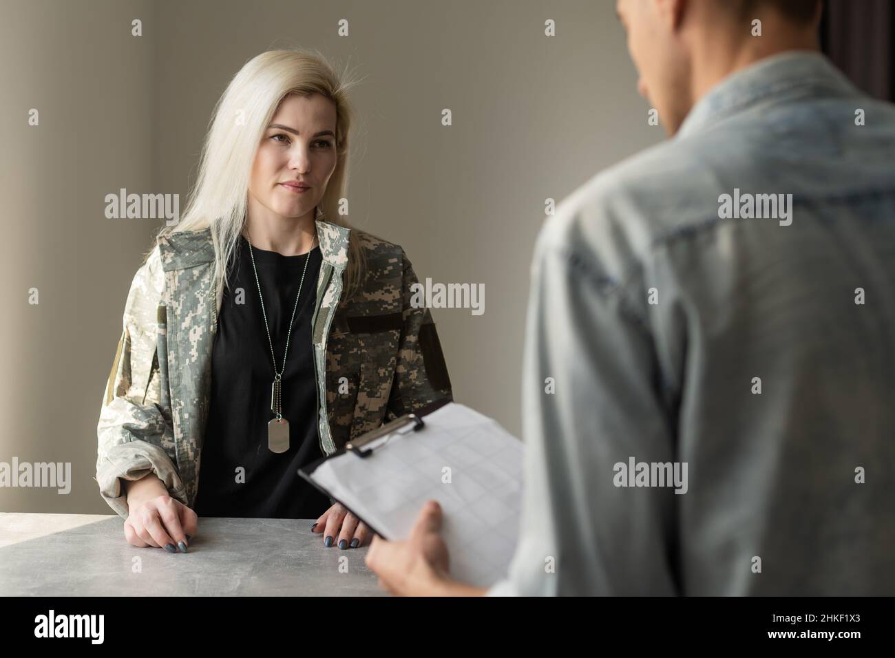 Patriotic military woman. Young patriotic military woman speaking with psychologist making notes Stock Photo
