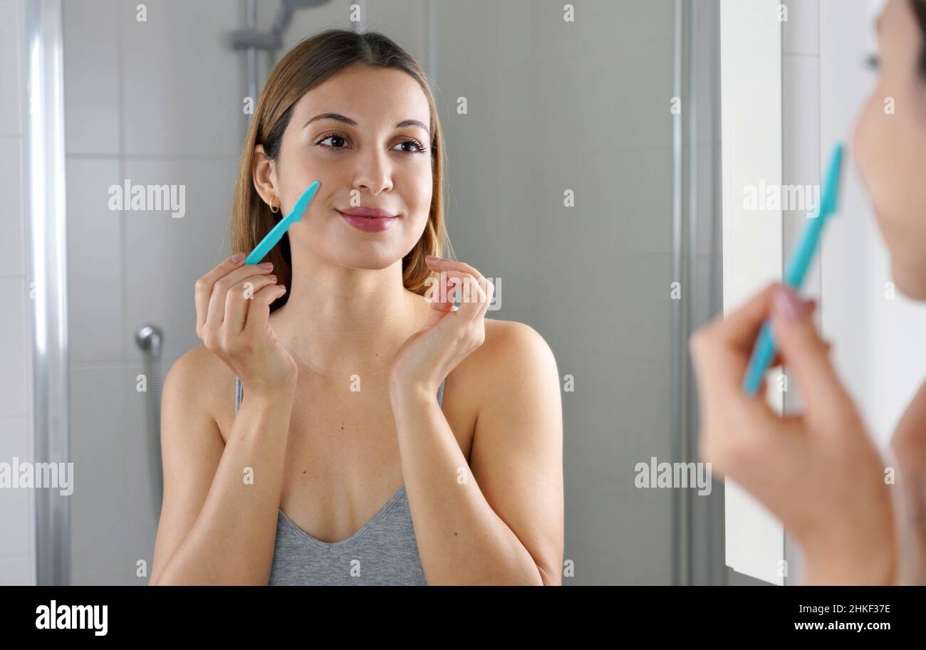 Beauty woman shaving her face by razor at home. Pretty girl using razor