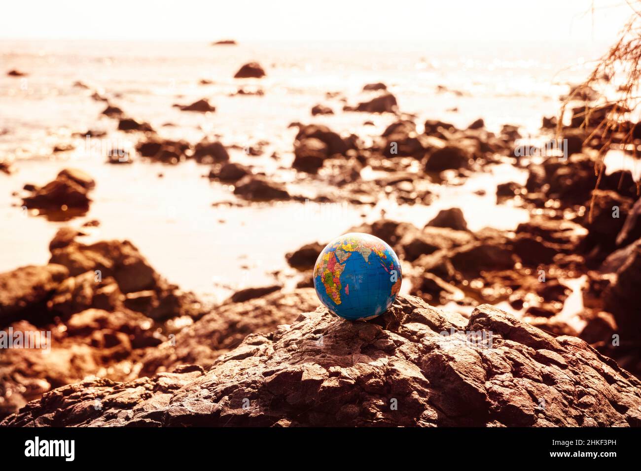 A globe on a rock on a coast by the sea Stock Photo