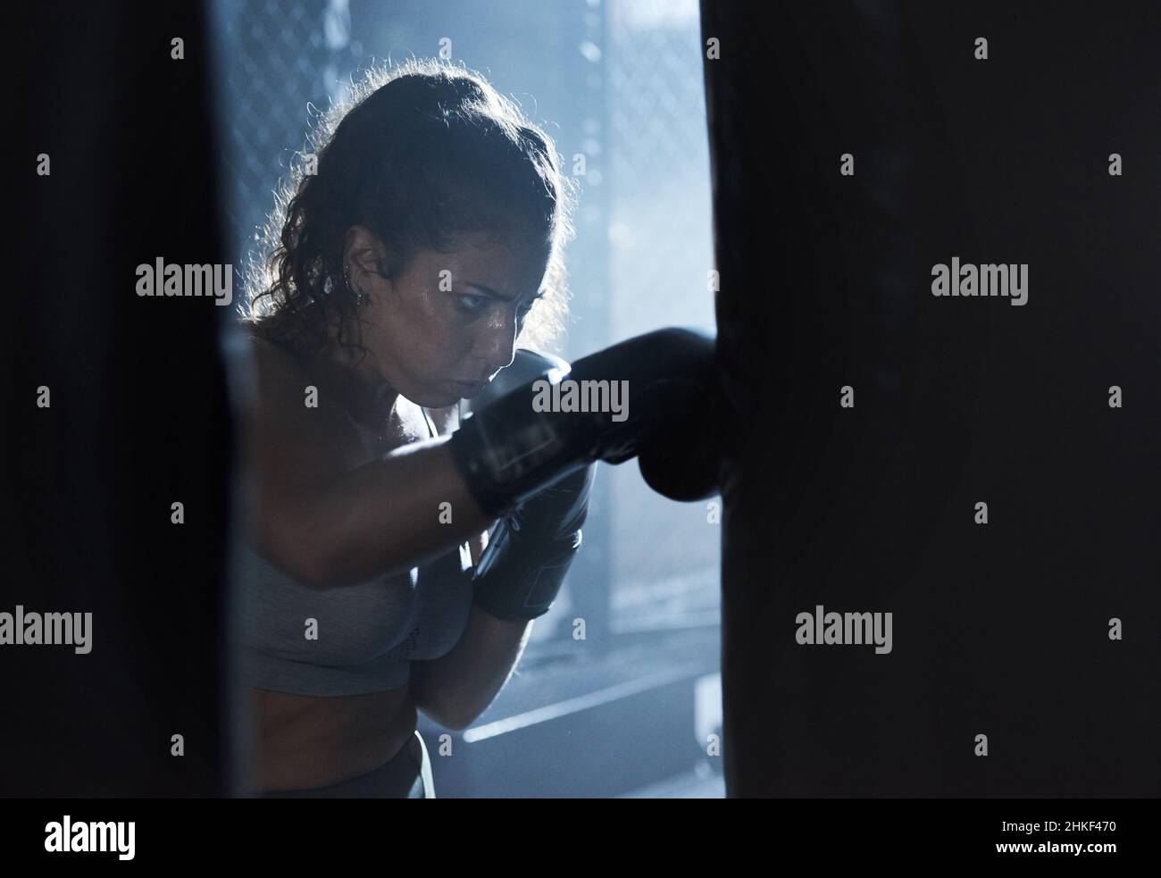 Turning pain into power. Shot of a sporty young woman boxing in a gym. Stock Photo