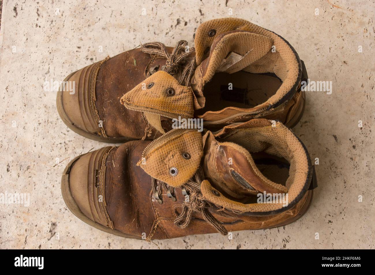 Pair of men's brown work boots - worn out splits and holes beyond repair. From above, on pavement. Queensland Australia. Stock Photo