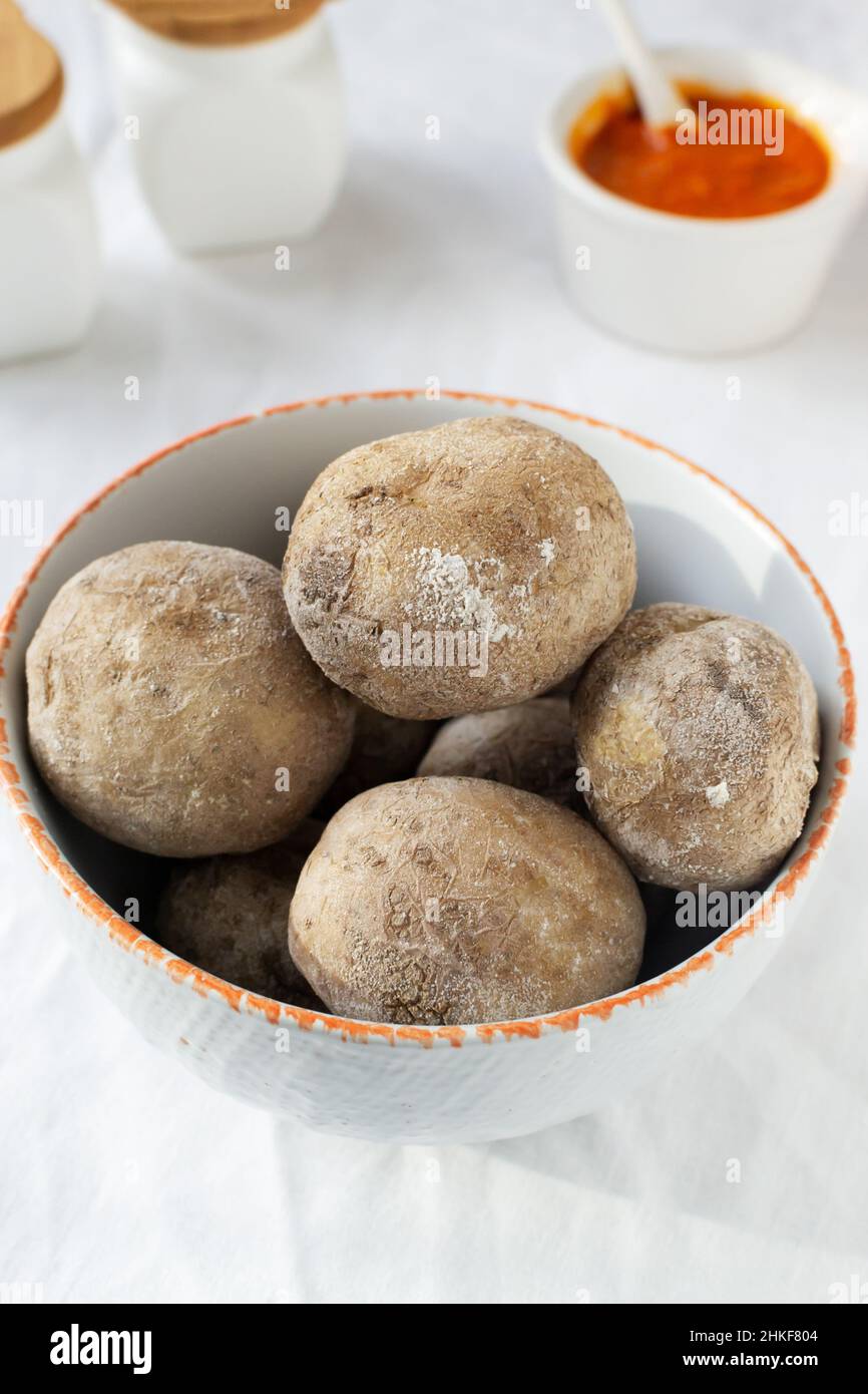 Potatoes on a white plate with red sauce on a white tablecloth. A traditional Canarian dish is papas arrugadas. Vegetables are boiled in water with a Stock Photo
