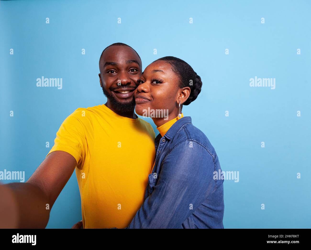 POV of people in relationship smiling in front of camera, taking pictures together in studio. Cheerful couple using phone in hand to take selfies and share romance. Partners hugging each other Stock Photo