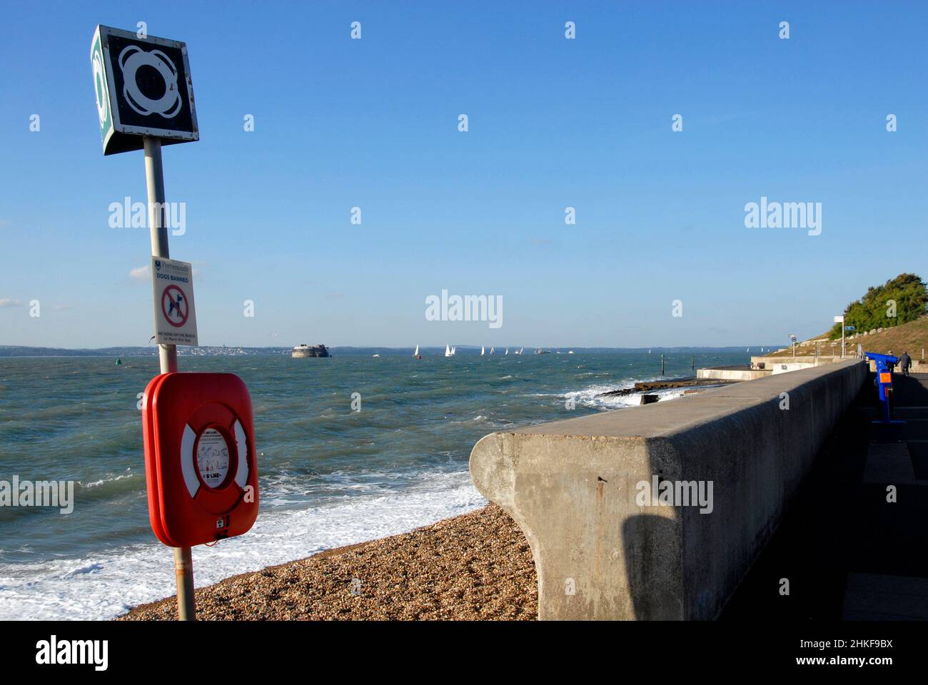 Lifebelt in case, Portsmouth, Hampshire, England with yachts at sea in the distance and a martello tower and the Isle of Wight Stock Photo
