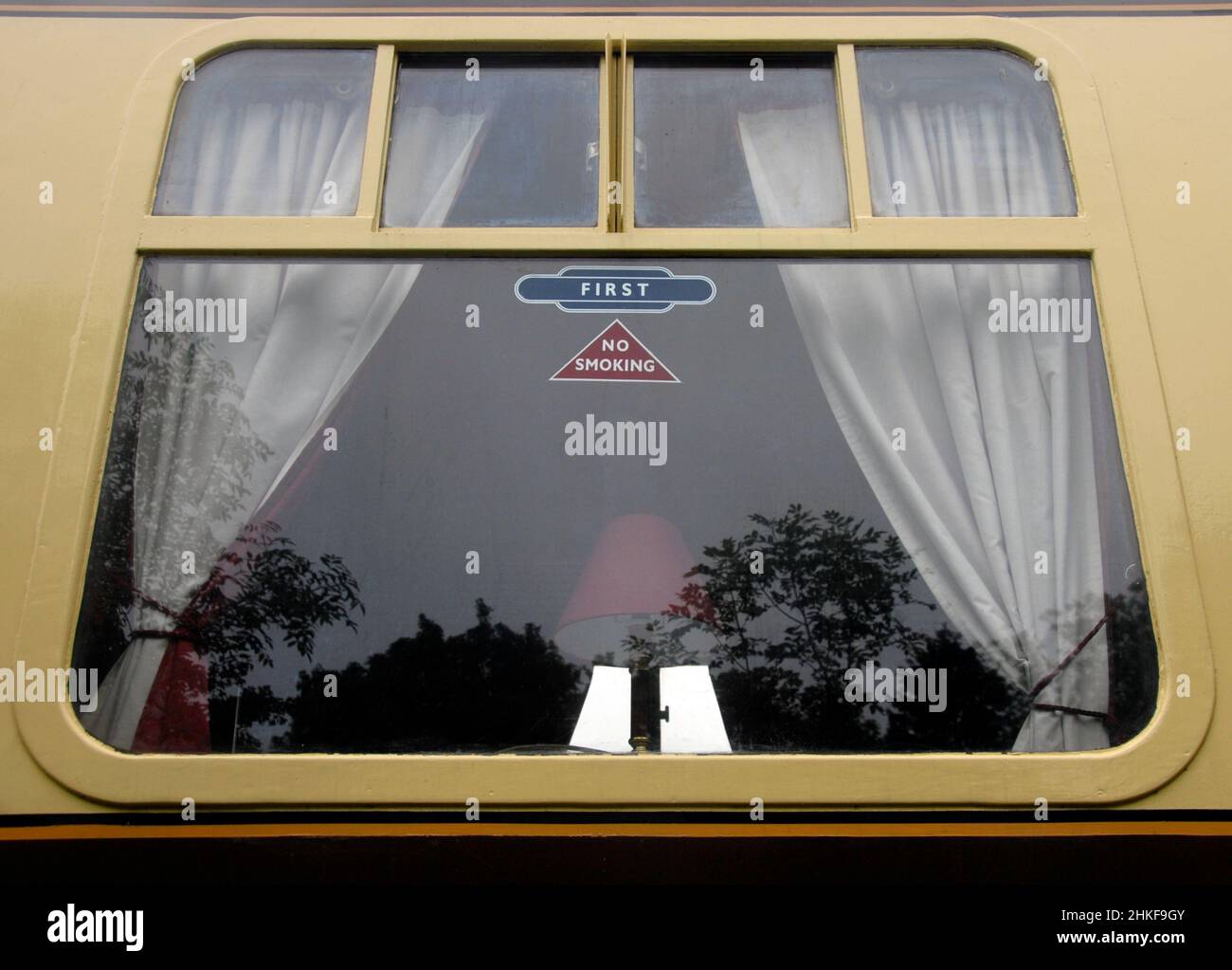 Window of old-style railway compartment with sign for First Class and No Smoking on the glass and table lamp visible through the window Stock Photo