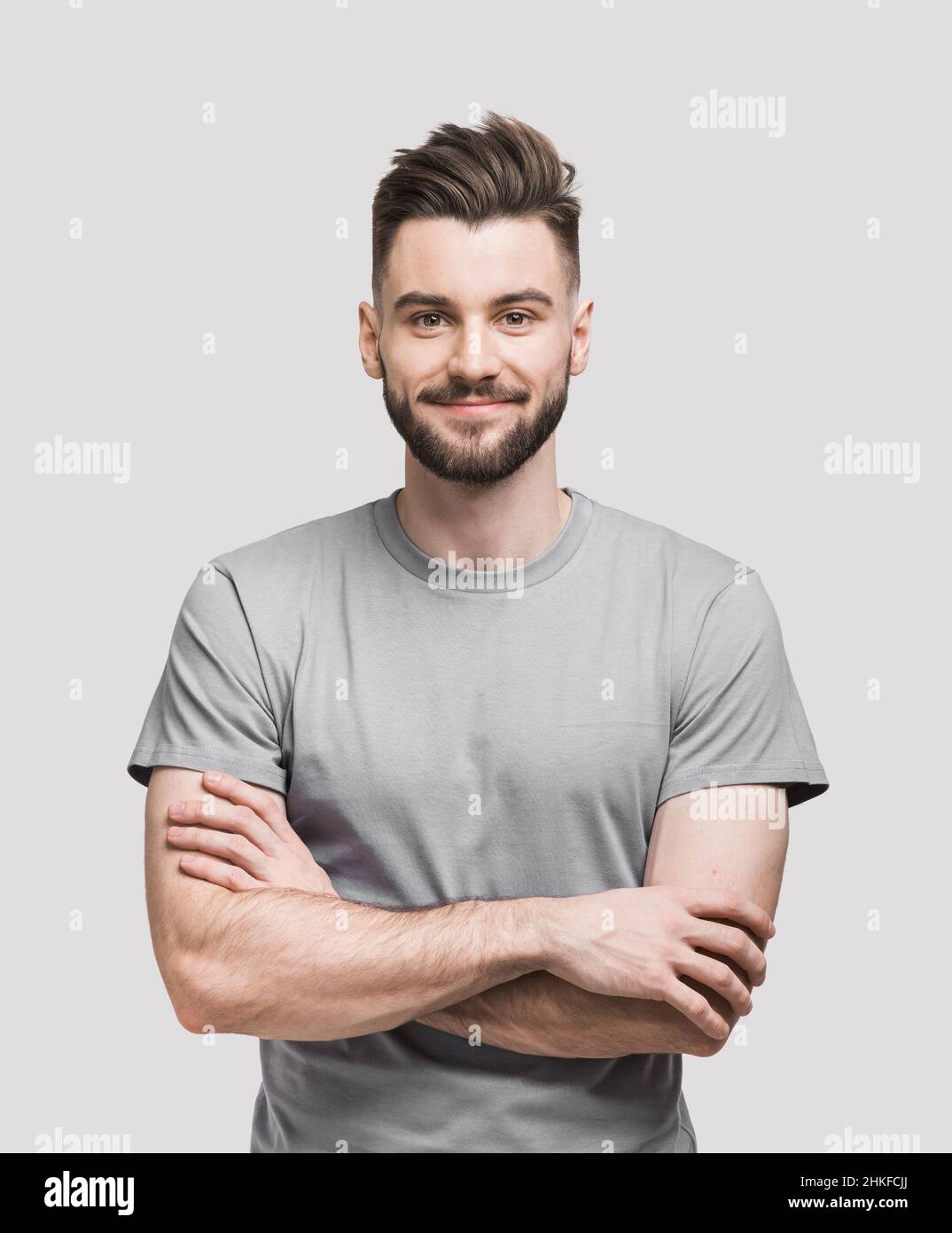 Smiling young man studio portrait isolated. Joyful handsome men with crossed arms studio shot. Isolated on gray background, people, beauty concept Stock Photo