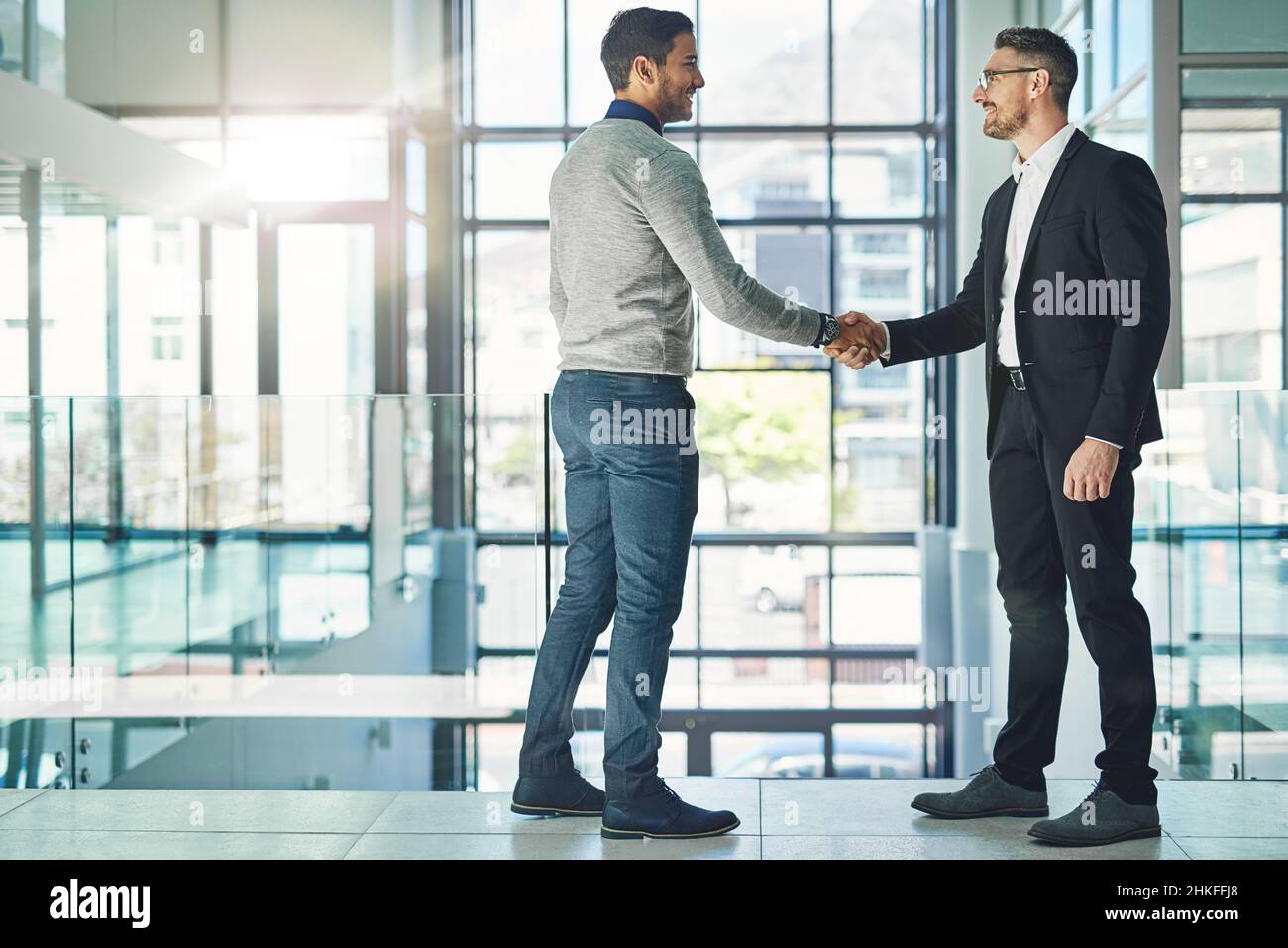 You deserve this promotion. Shot of two businessmen shaking hands together in an office. Stock Photo